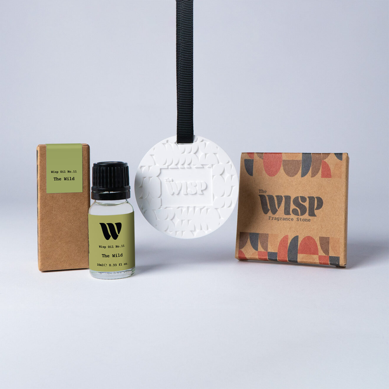 Bottle of the 10ml Wisp home fragrance oil No.11 The Wild which has notes of floral lily of the valley and persimmon, with a premium wisp branded fragrance stone to hang in car or wardrobe. The perfect small gift.