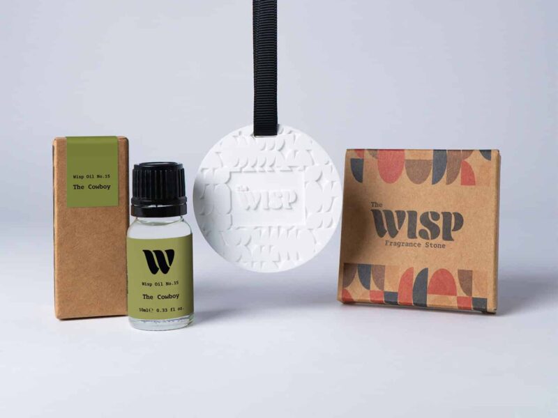 Bottle of the 10ml Wisp home fragrance oil No.15 The Cowboy which has notes of sandalwood and cedarwood, with a premium wisp branded fragrance stone to hang in car or wardrobe. The perfect small gift.
