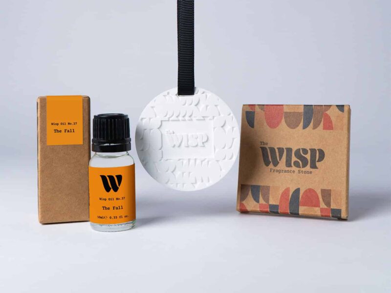 Bottle of the 10ml Wisp home fragrance oil No.27 The Fall which has notes of cedarwood, cardamom and pink pepper, with a premium wisp branded fragrance stone to hang in car or wardrobe. The perfect small gift.